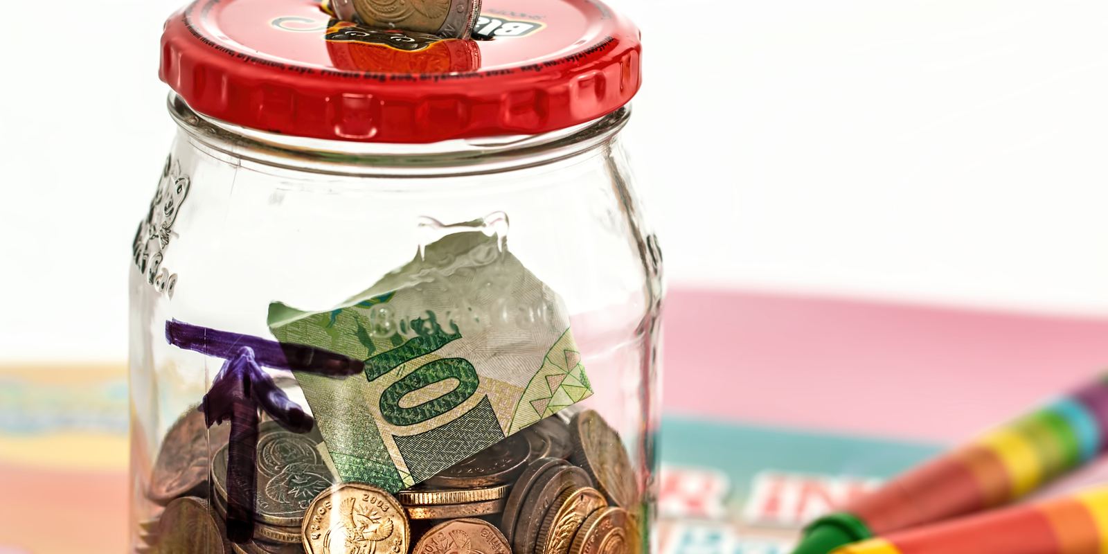 A pink piggy bank with coins beside it