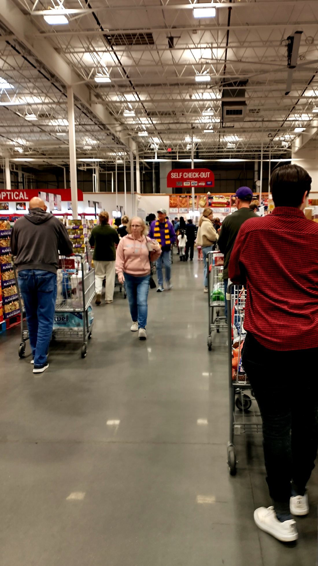 Shoppers with carts standing in a checkout line at a Costco warehouse