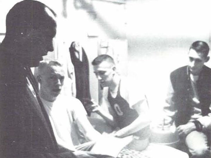 Coach Bill Bowerman giving advice to University of Oregon runners including a young Phil Knight