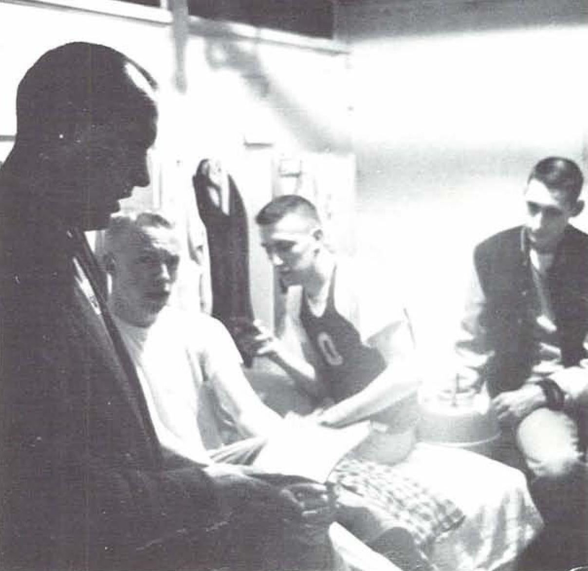 Coach Bill Bowerman giving advice to University of Oregon runners including a young Phil Knight